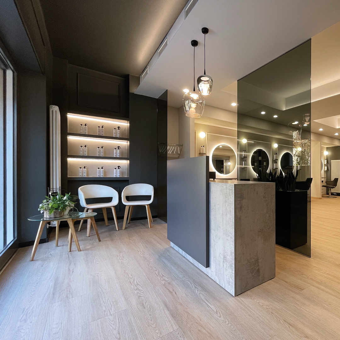 Immagine della reception con focus su bancone grigio. Visuale anche su zona stilistica con pareti bianche e blu